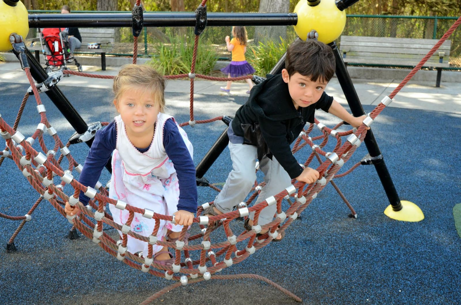 Two children crossing a rope bridge on the climbing structure