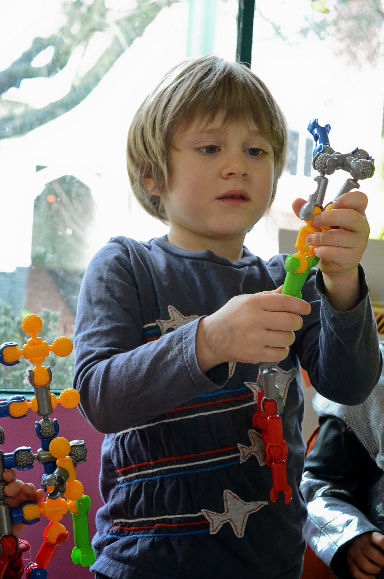A child holding up a construction toy they have built