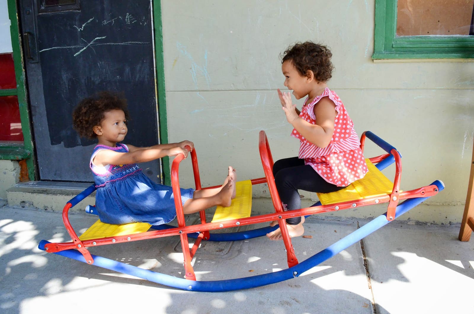 Two children riding a seesaw in the yard